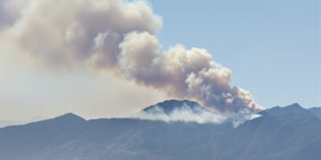 Humo de incendio forestal en zona montañosa de Córdoba, Argentina, con vegetación de pastizal.