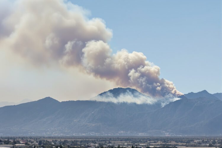 Humo de incendio forestal en zona montañosa de Córdoba, Argentina, con vegetación de pastizal.