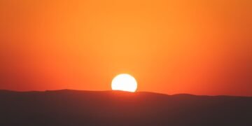 Extenso campo de paneles solares en India bajo luz crepuscular, símbolo de la transición energética que mantiene planas las e