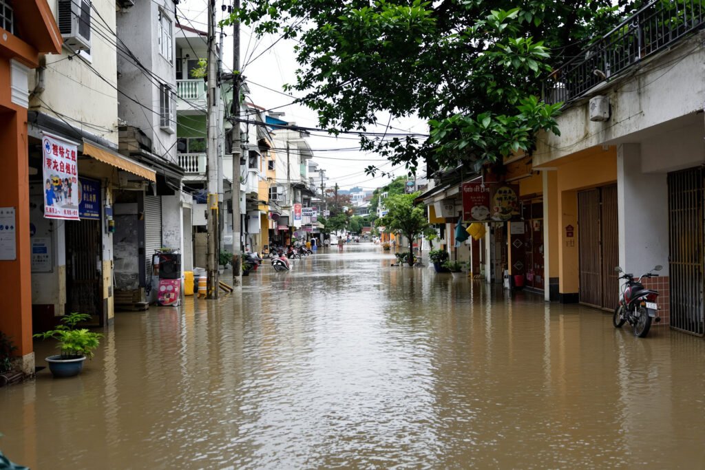 Calles inundadas en una ciudad asiática durante la temporada de monzones, con edificios reflejados en el agua.