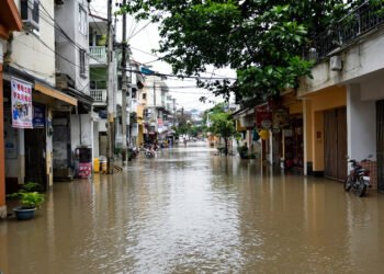 Calles inundadas en una ciudad asiática durante la temporada de monzones, con edificios reflejados en el agua.