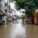 Calles inundadas en una ciudad asiática durante la temporada de monzones, con edificios reflejados en el agua.