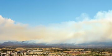 Paisaje post incendio forestal en Hawái con humo residual y vegetación quemada, similar al escenario de Maui tras los incendi
