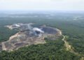 Vista aérea de la devastación por minería ilegal en la Amazonía peruana, con pozas marrones rodeadas de bosque.