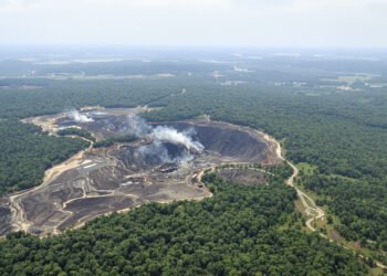 Vista aérea de la devastación por minería ilegal en la Amazonía peruana, con pozas marrones rodeadas de bosque.