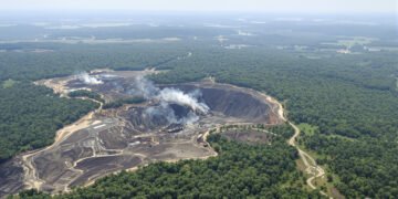 Vista aérea de la devastación por minería ilegal en la Amazonía peruana, con pozas marrones rodeadas de bosque.