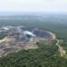Vista aérea de la devastación por minería ilegal en la Amazonía peruana, con pozas marrones rodeadas de bosque.