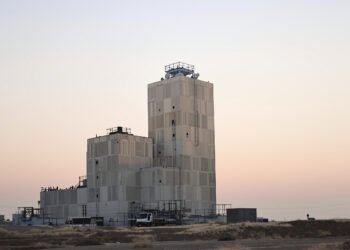 Torre industrial de hormigón en China durante el atardecer, con bloques de concreto apilados.