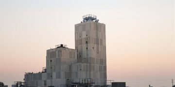 Torre industrial de hormigón en China durante el atardecer, con bloques de concreto apilados.