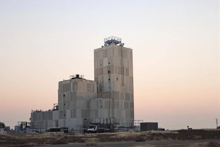 Torre industrial de hormigón en China durante el atardecer, con bloques de concreto apilados.