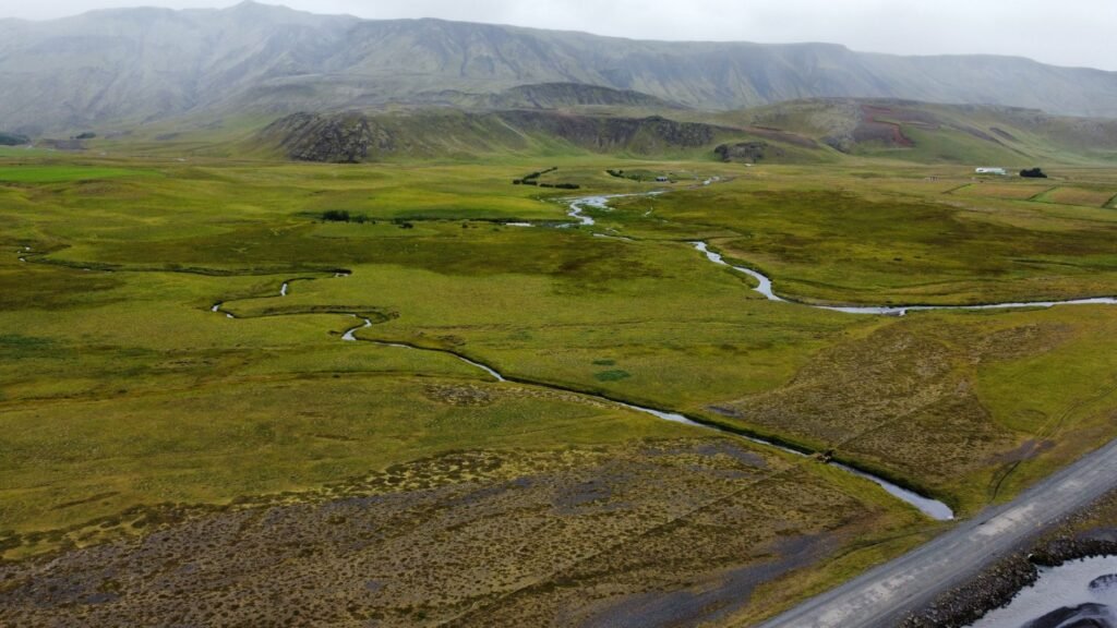 Paisaje de permafrost descongelándose en región ártica, con suelo erosionado y cuerpos de agua.
