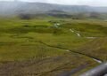 Paisaje de permafrost descongelándose en región ártica, con suelo erosionado y cuerpos de agua.