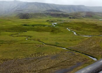 Paisaje de permafrost descongelándose en región ártica, con suelo erosionado y cuerpos de agua.