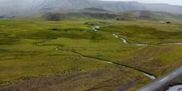 Paisaje de permafrost descongelándose en región ártica, con suelo erosionado y cuerpos de agua.