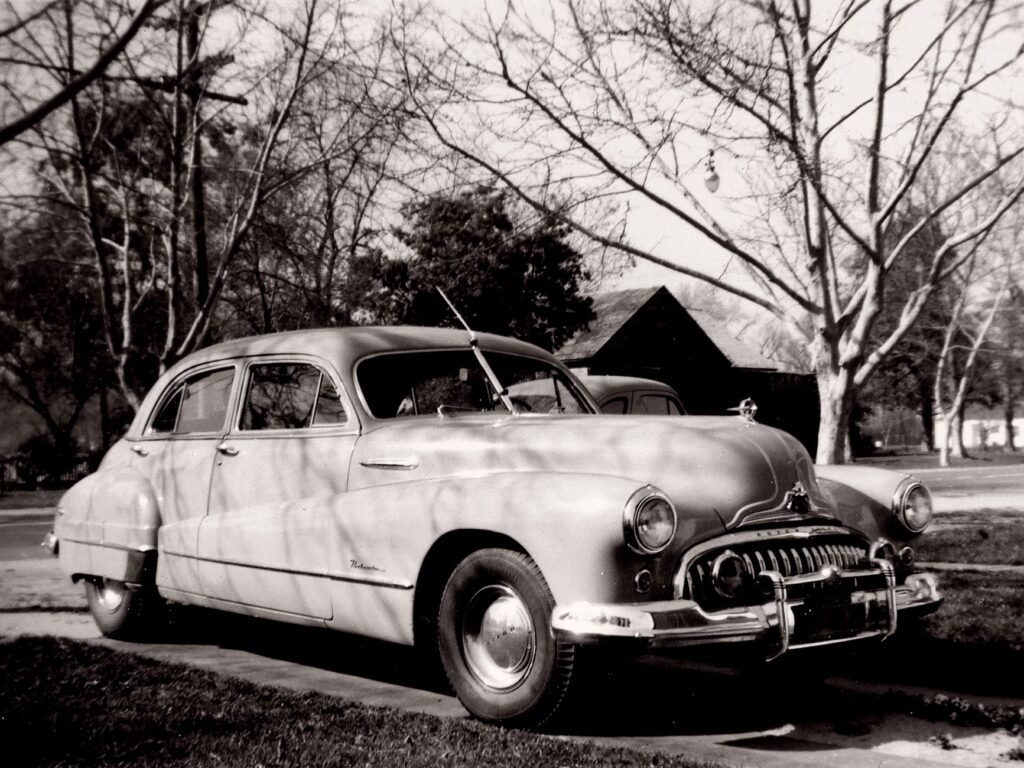 Autopista suburbana estadounidense con autos vintage, símbolo del Sueño Americano inventado por la industria petrolera.