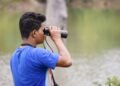 Observador de aves en la naturaleza documentando biodiversidad con binoculares