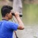 Observador de aves en la naturaleza documentando biodiversidad con binoculares
