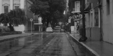 Calle inundada con vehículos sumergidos en agua tras lluvias extremas en zona urbana.