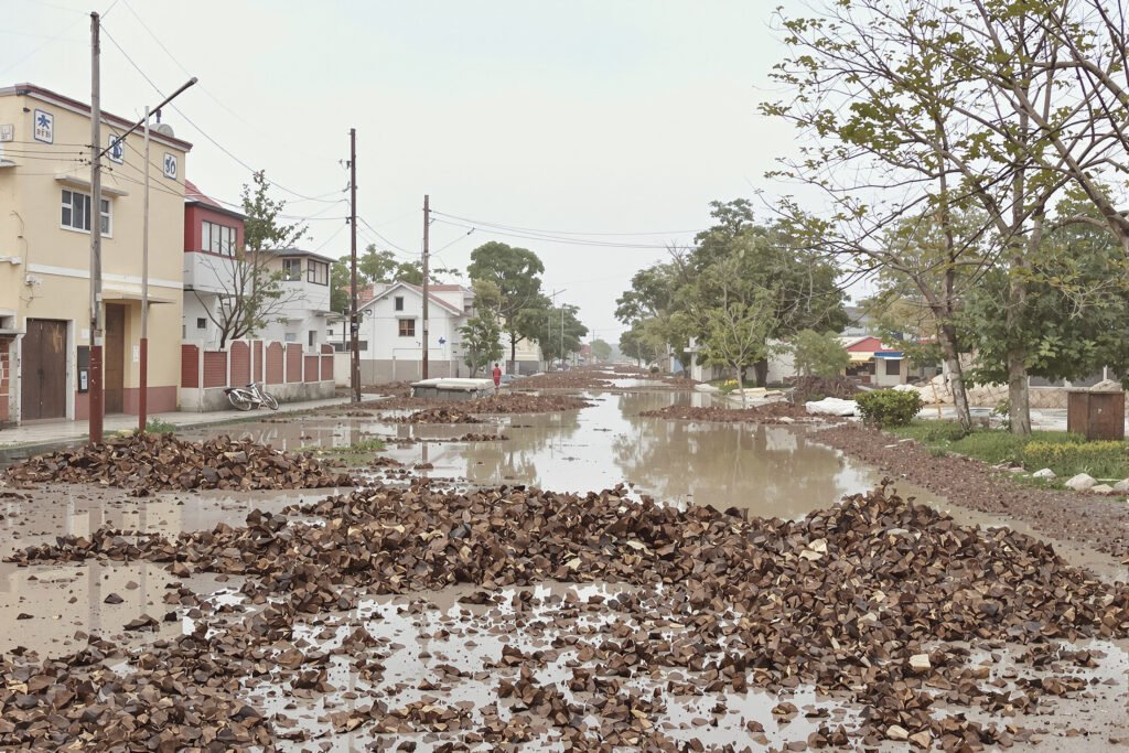Calle inundada con agua fangosa y escombros tras lluvias torrenciales en zona urbana.