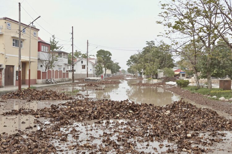 Calle inundada con agua fangosa y escombros tras lluvias torrenciales en zona urbana.