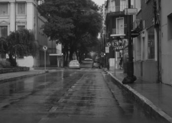 Calle inundada con vehículos bajo el agua tras lluvias torrenciales en zona urbana.