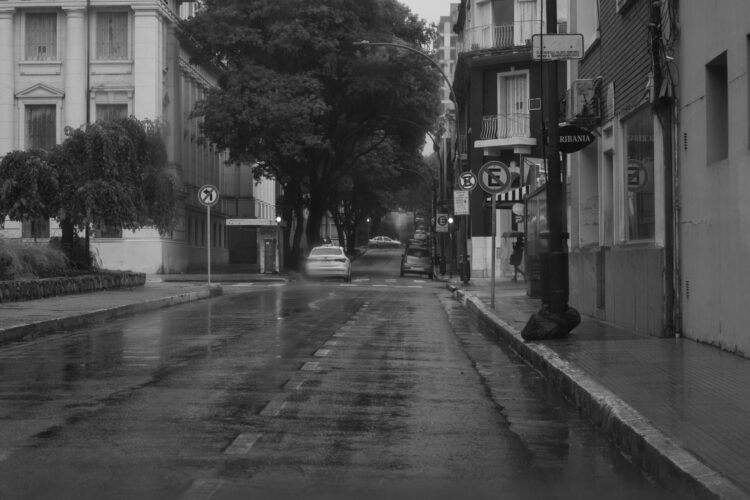 Calle inundada con vehículos bajo el agua tras lluvias torrenciales en zona urbana.