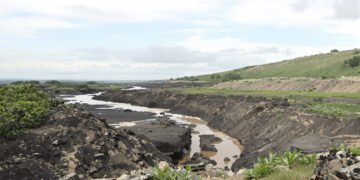 Paisaje de río en Colombia afectado por la minería de oro de aluvión, con maquinaria en las orillas.