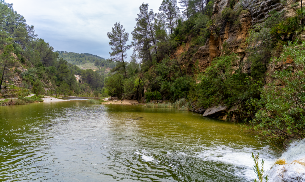 Río de montaña desbordado arrastrando escombros tras lluvias torrenciales en zona montañosa.