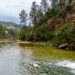 Río de montaña desbordado arrastrando escombros tras lluvias torrenciales en zona montañosa.