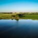 Vista aérea de un humedal rodeado de pastizales y espejos de agua al atardecer, representativo de reservas naturales urbanas