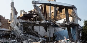Edificio dañado por un terremoto con escombros y grietas estructurales.