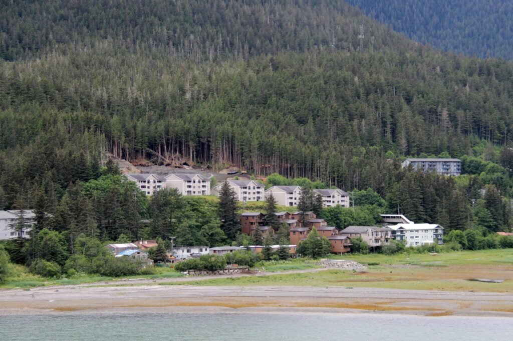 Aldea costera de Alaska devastada por tormenta, con casas destruidas y escombros dispersos sobre la tundra.